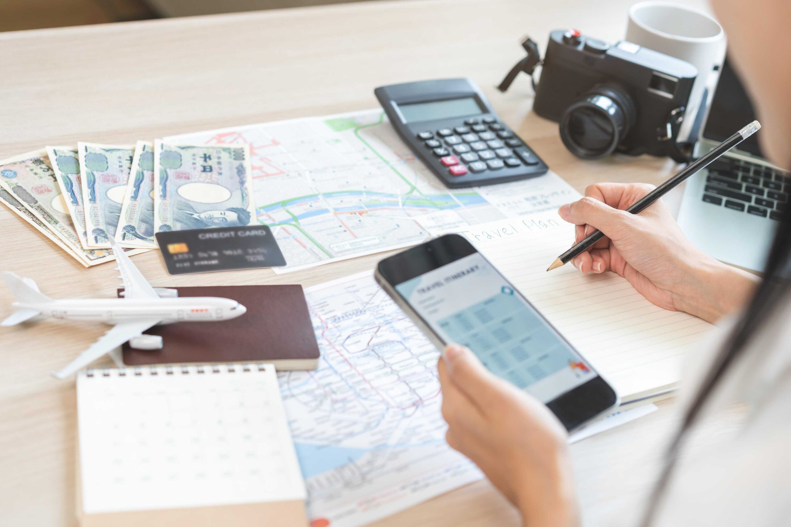 Desk with passport, model plan and camera laid out as woman plans her holiday.